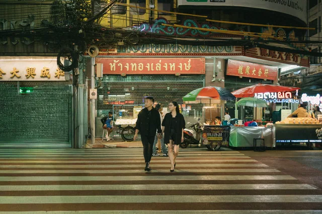 Mauric and Nadya walking hand in hand across a city street at night